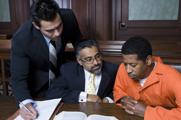 man in orange jumpsuit with lawyers